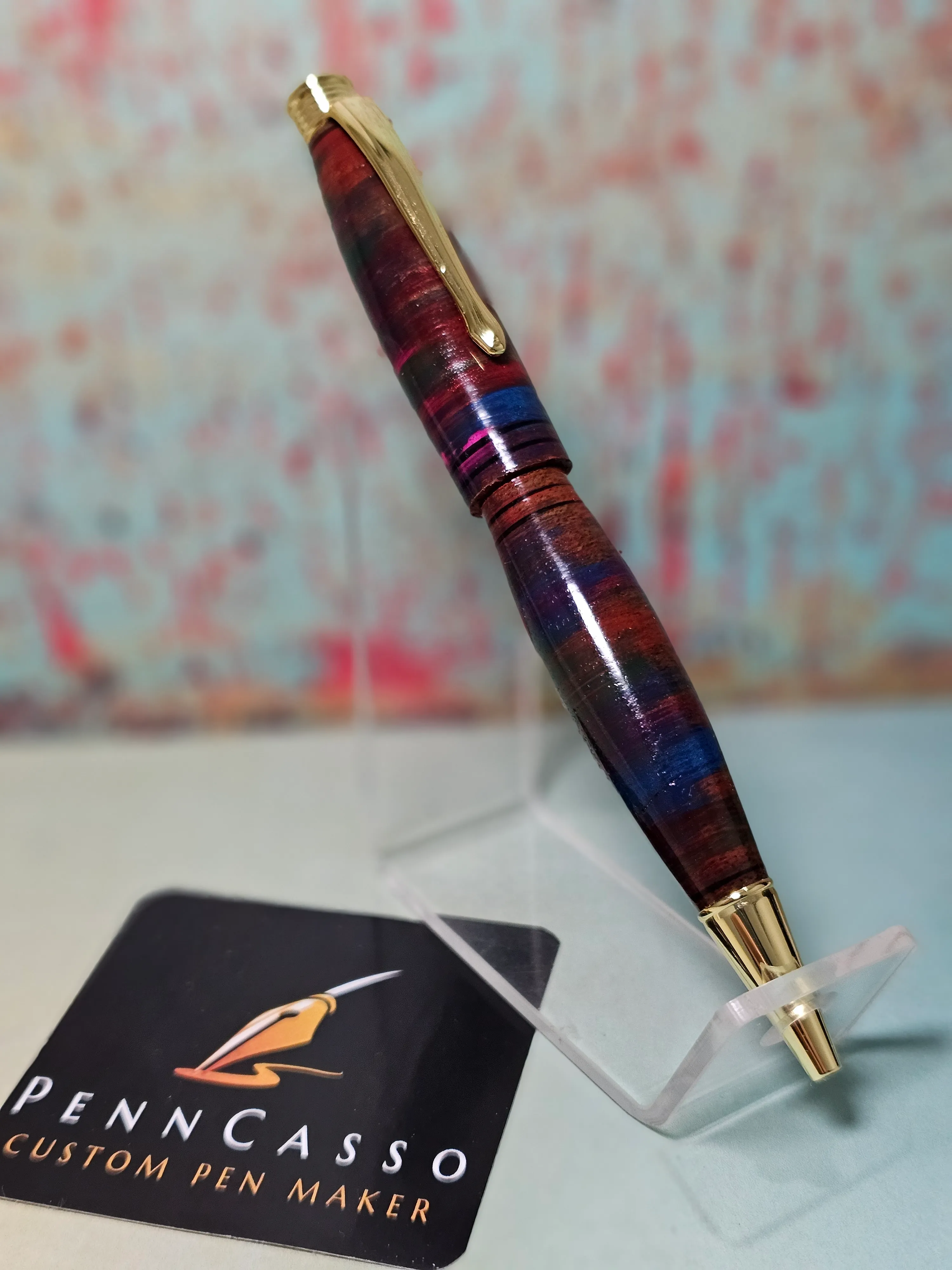 A handcrafted PennCasso pen with a gold clip on a display stand